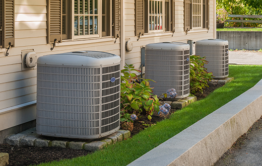 A row of air conditioners sit outside condos